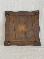 Underside of the wooden trivet frame, showing the plank back and four dark turned bun feet