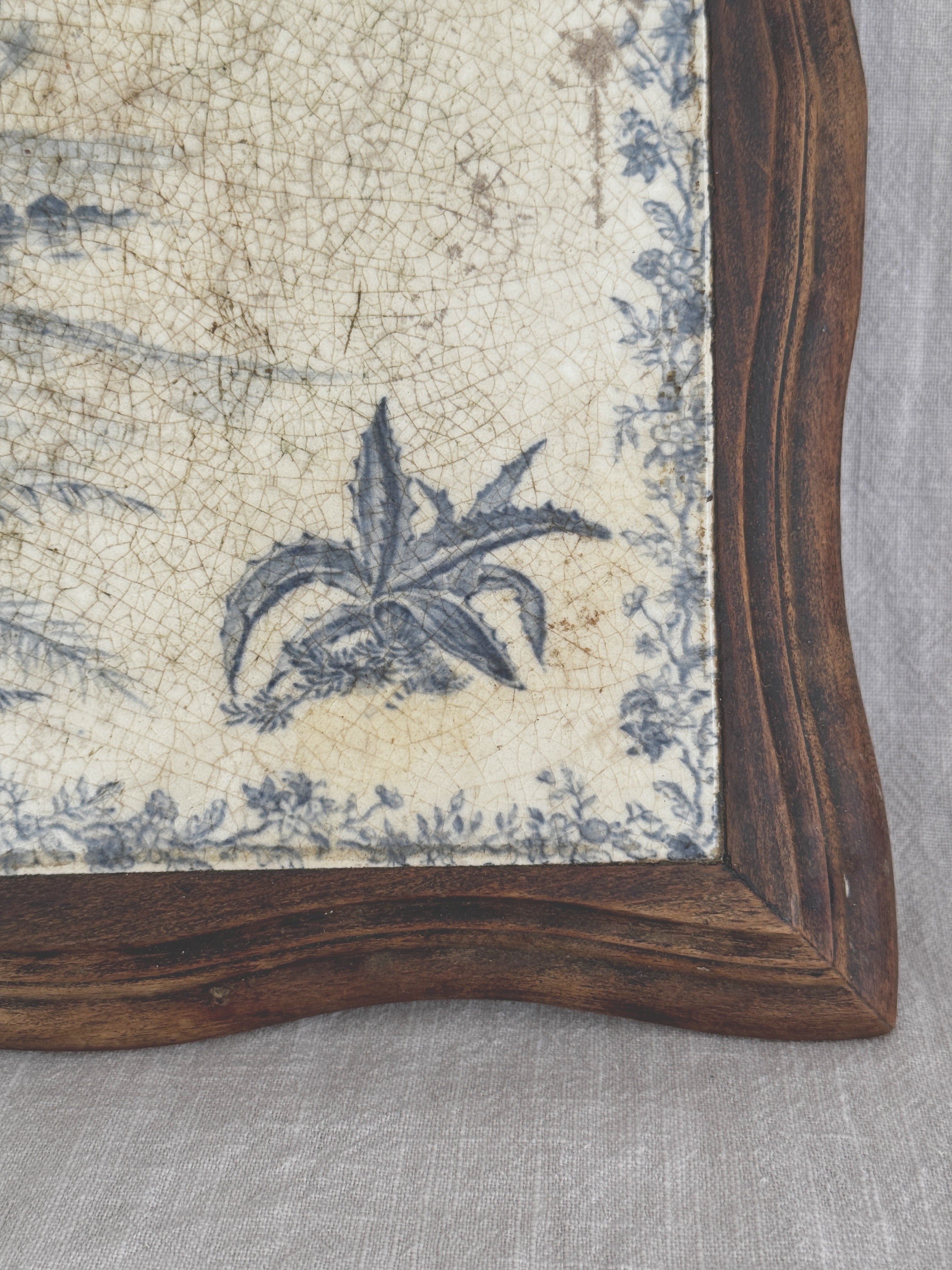 Close-up of the lower corner of the tile, showing an agave in blue transfer print and dense allover crazing