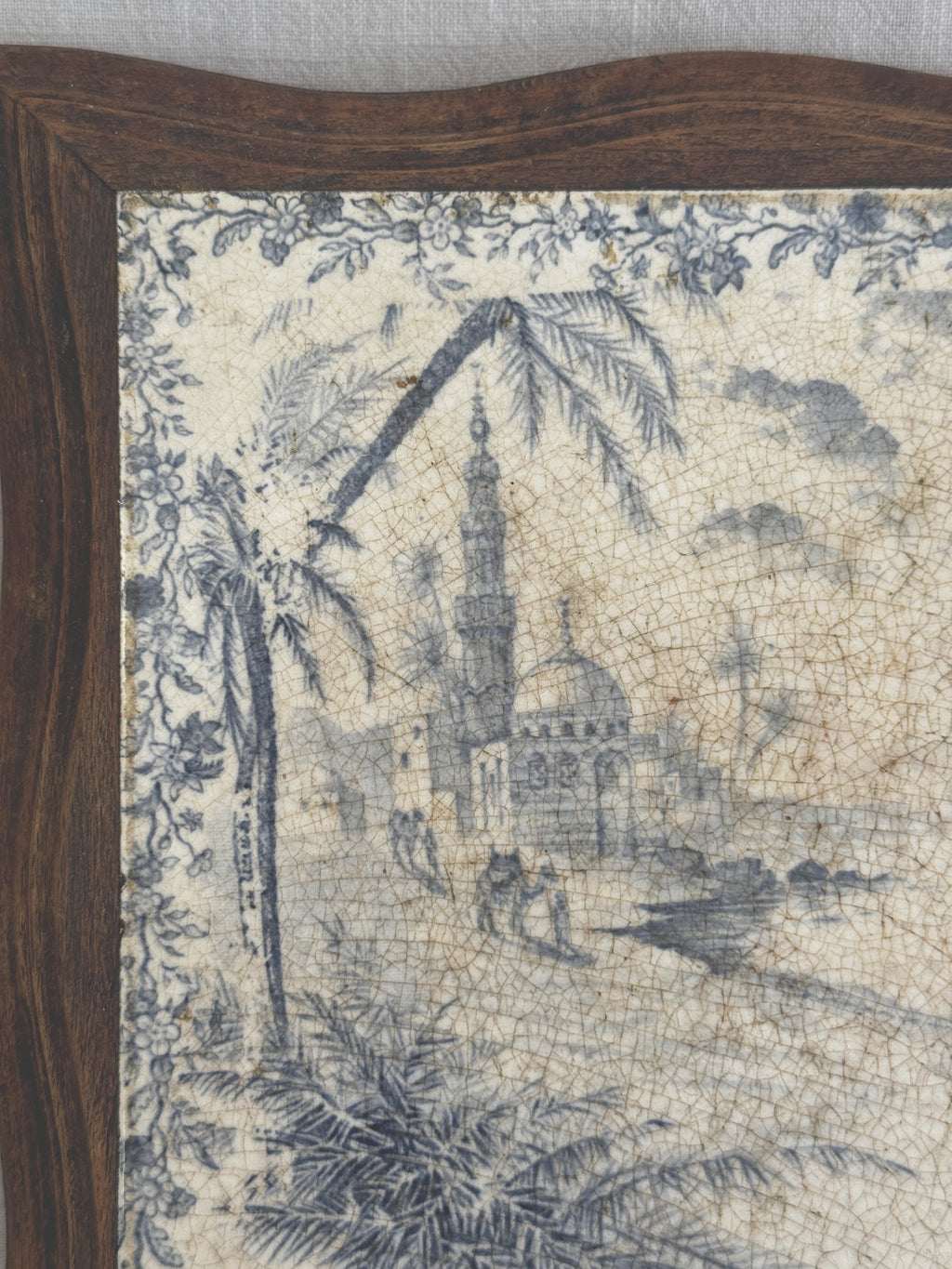 Close-up of the mosque, minaret and palm trees in blue transfer print beside the wooden frame edge