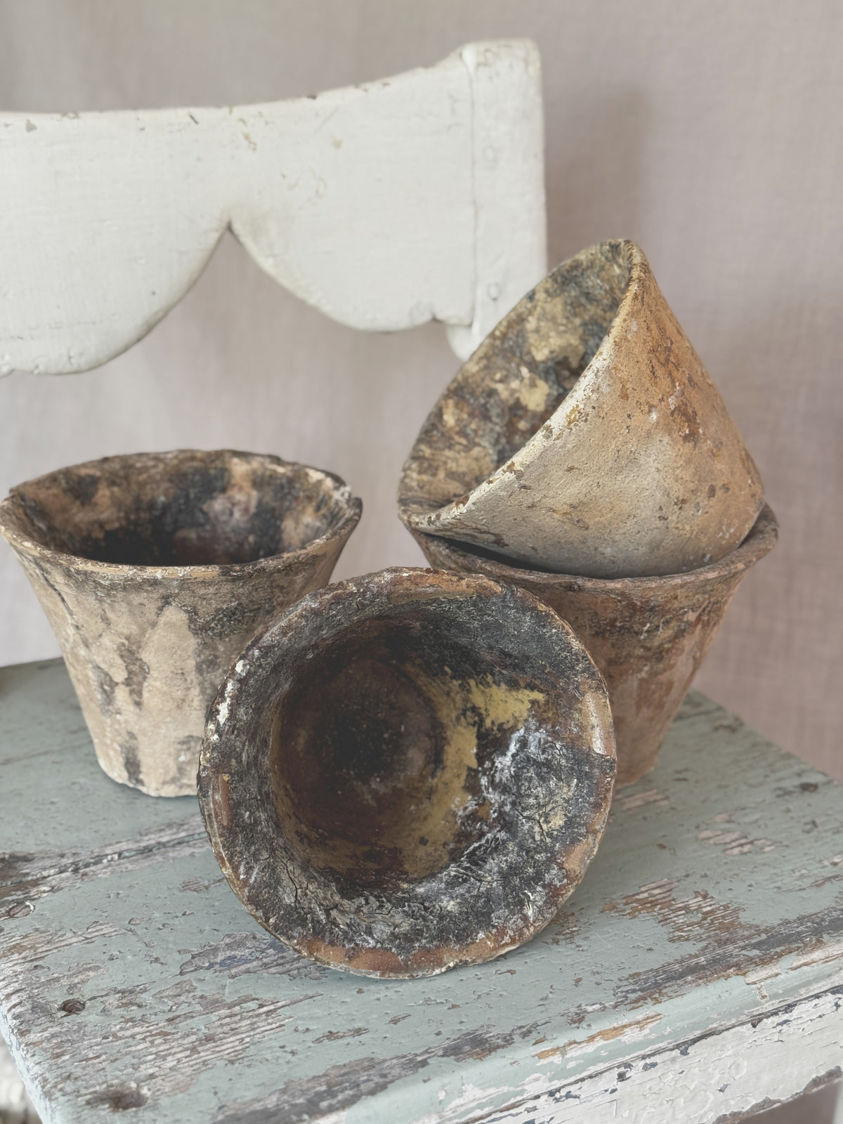 Four antique French terracotta resin pots with dark pine resin patina, grouped on a painted stool
