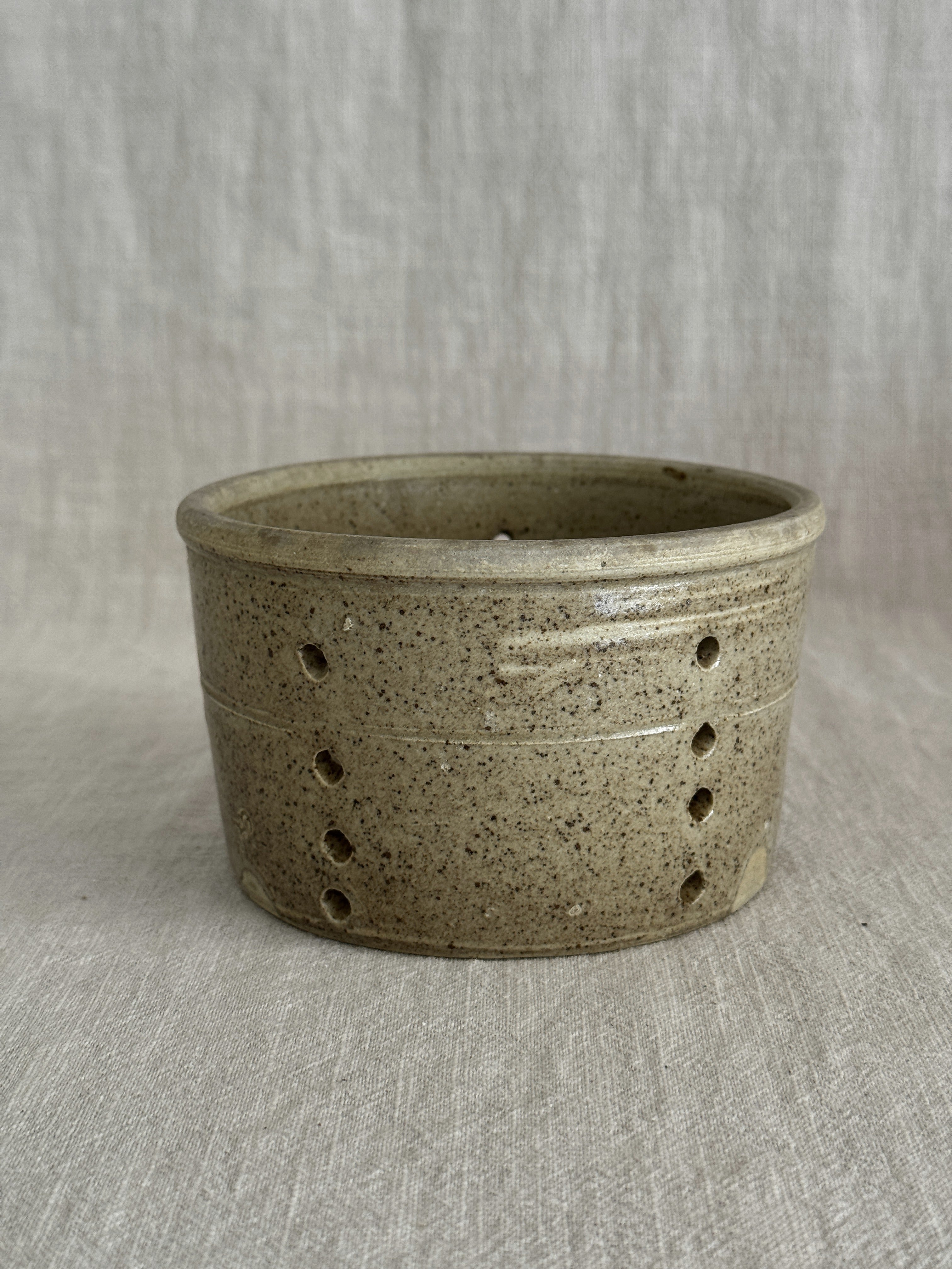 Vintage French stoneware faisselle cheese mould with a speckled olive salt glaze and rows of pierced holes