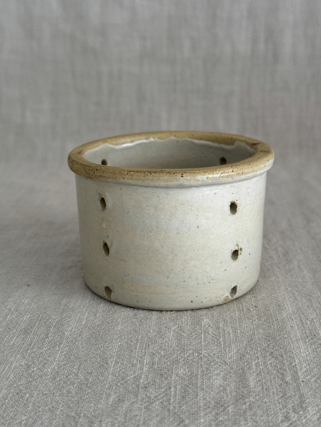 The smaller French faisselle, pale grey-cream stoneware with an ochre rolled rim and pierced walls