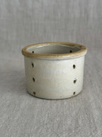 The smaller French faisselle, pale grey-cream stoneware with an ochre rolled rim and pierced walls