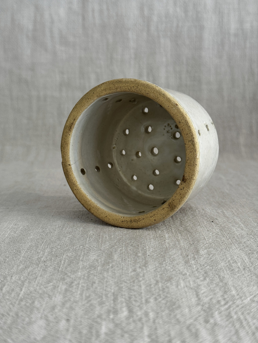Side view of the small French faisselle, glaze skips visible at the rim