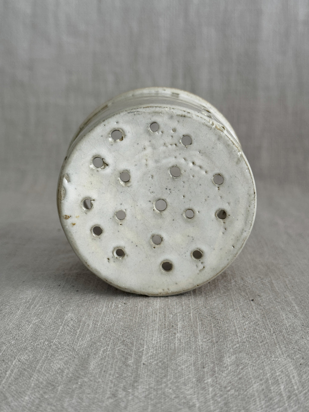 Interior of the small stoneware cheese mould with drainage holes across the base