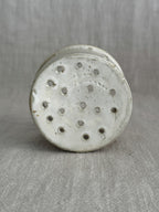 Interior of the small stoneware cheese mould with drainage holes across the base