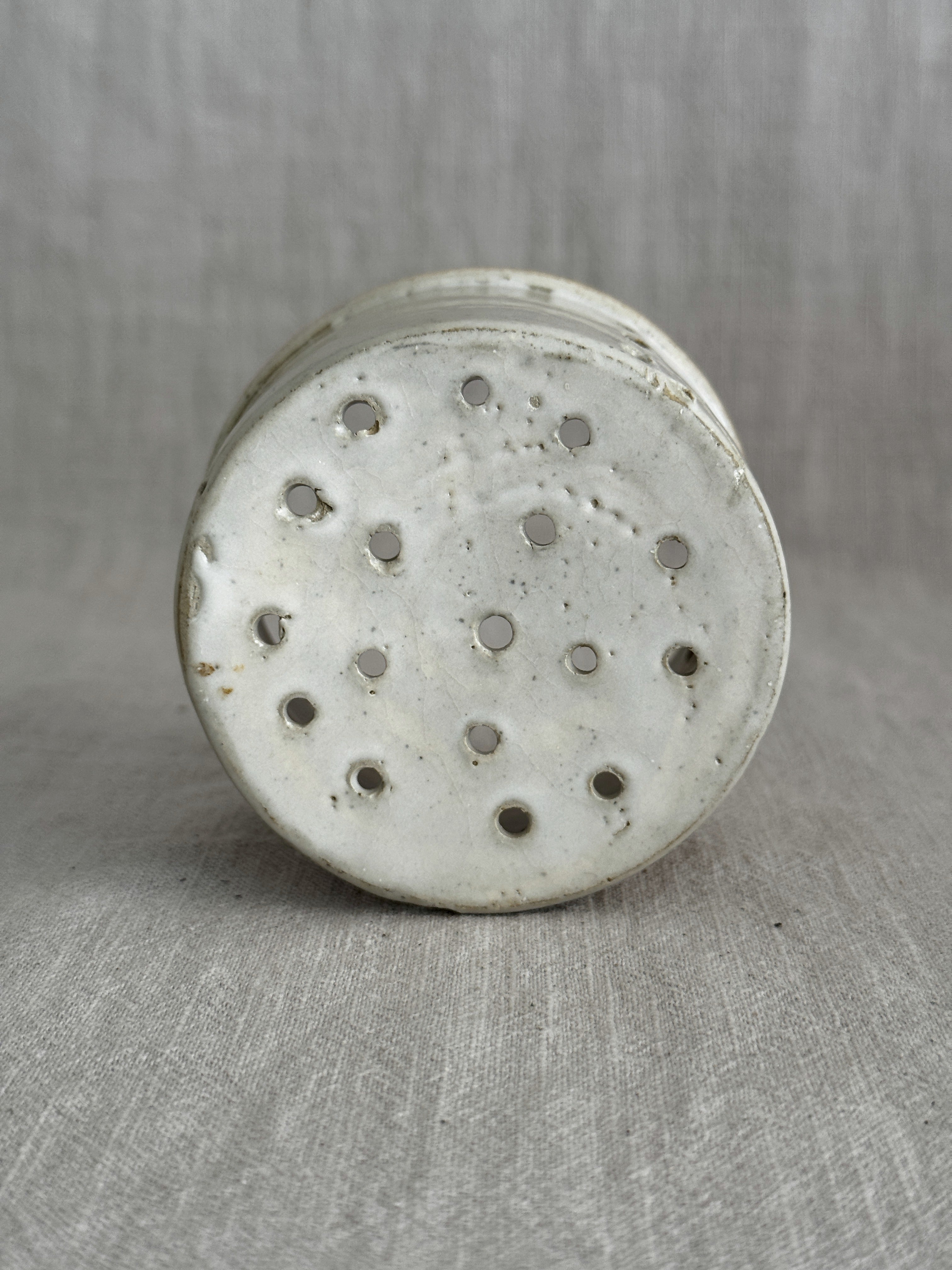 Interior of the small stoneware cheese mould with drainage holes across the base