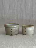 A pair of antique French faisselle cheese moulds in cream-glazed stoneware, standing side by side