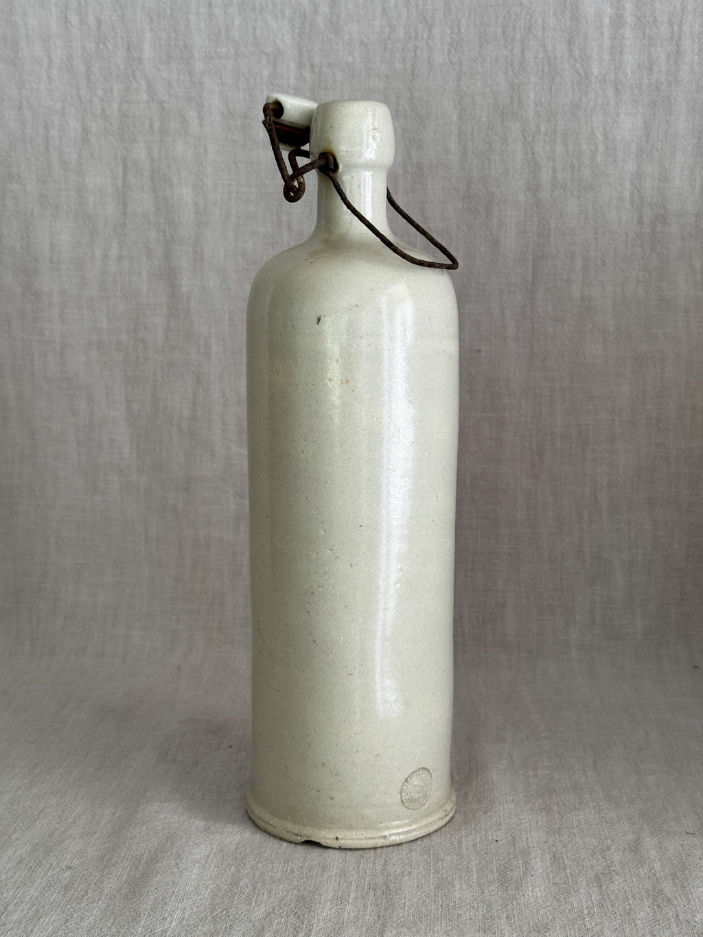 Tall antique French stoneware bottle in pale grès with an iron bail and white porcelain stopper