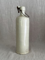 Tall antique French stoneware bottle in pale grès with an iron bail and white porcelain stopper