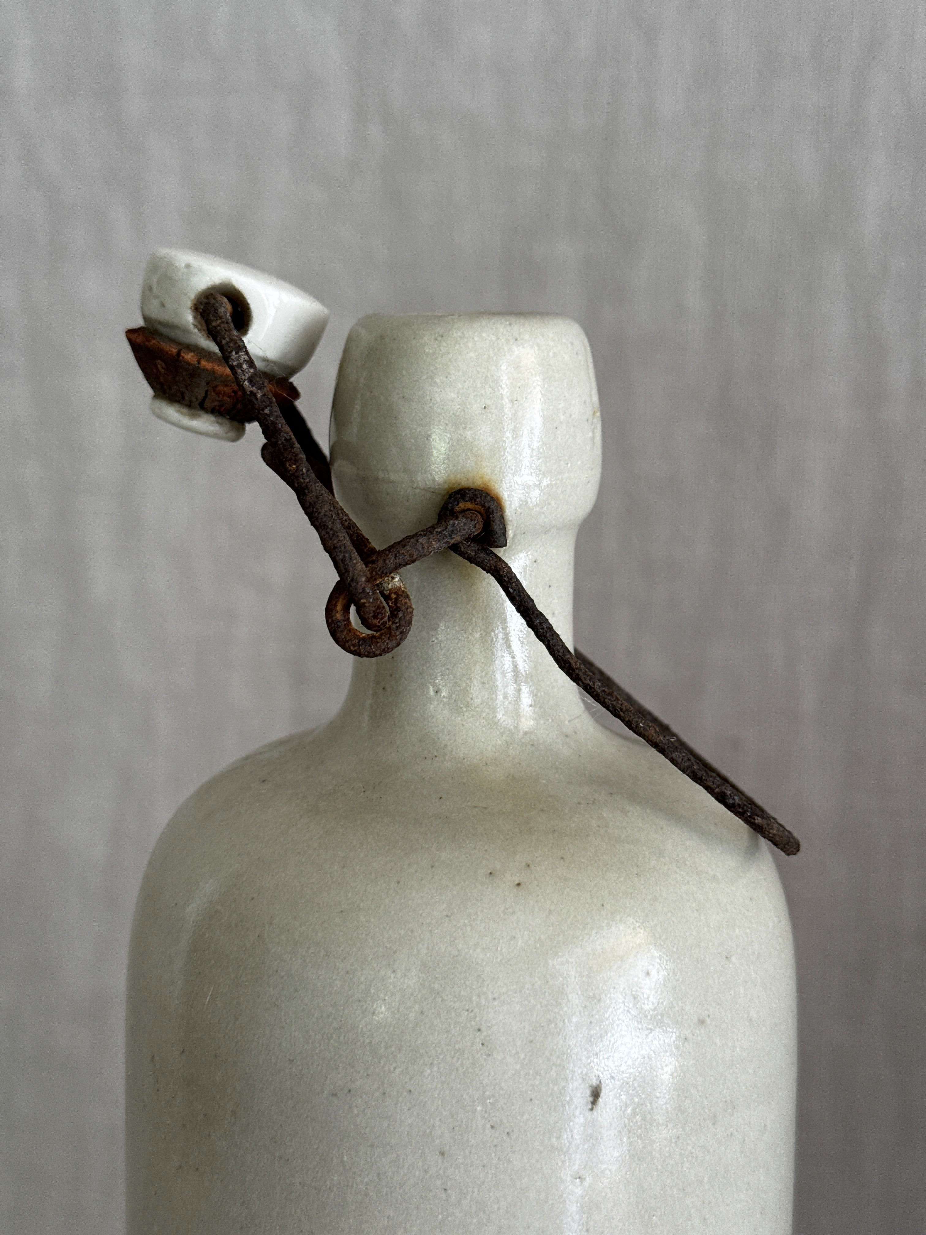 Close view of the rusted iron bail and porcelain stopper on the French grès bottle