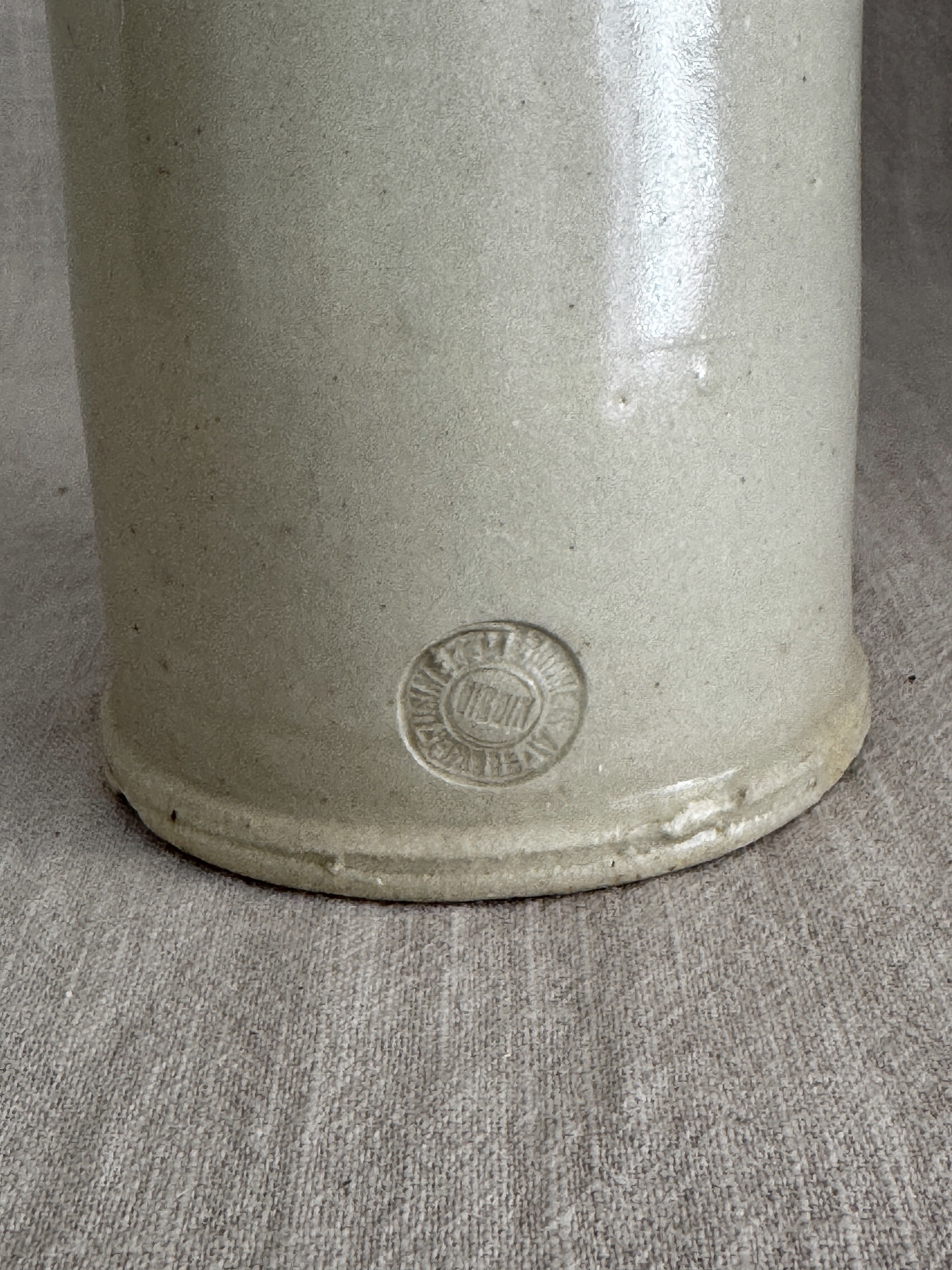 Worn round pottery stamp impressed low on the body of the French stoneware bottle