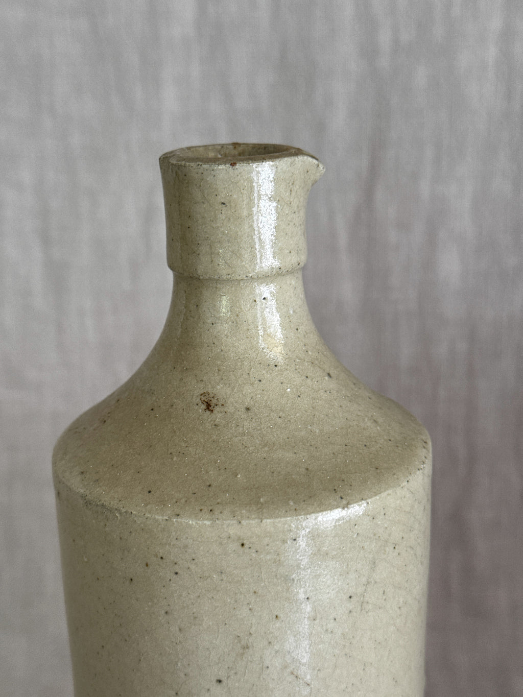 Close view of the bottle's sloping shoulder and short collar with its hand-pinched pouring lip