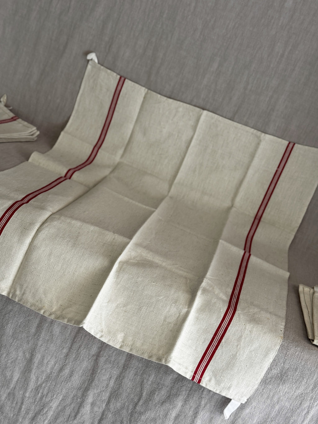 Vintage French red-striped linen torchon laid out flat, showing the full width and the soft fold creases