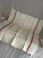 Vintage French red-striped linen torchon laid out flat, showing the full width and the soft fold creases