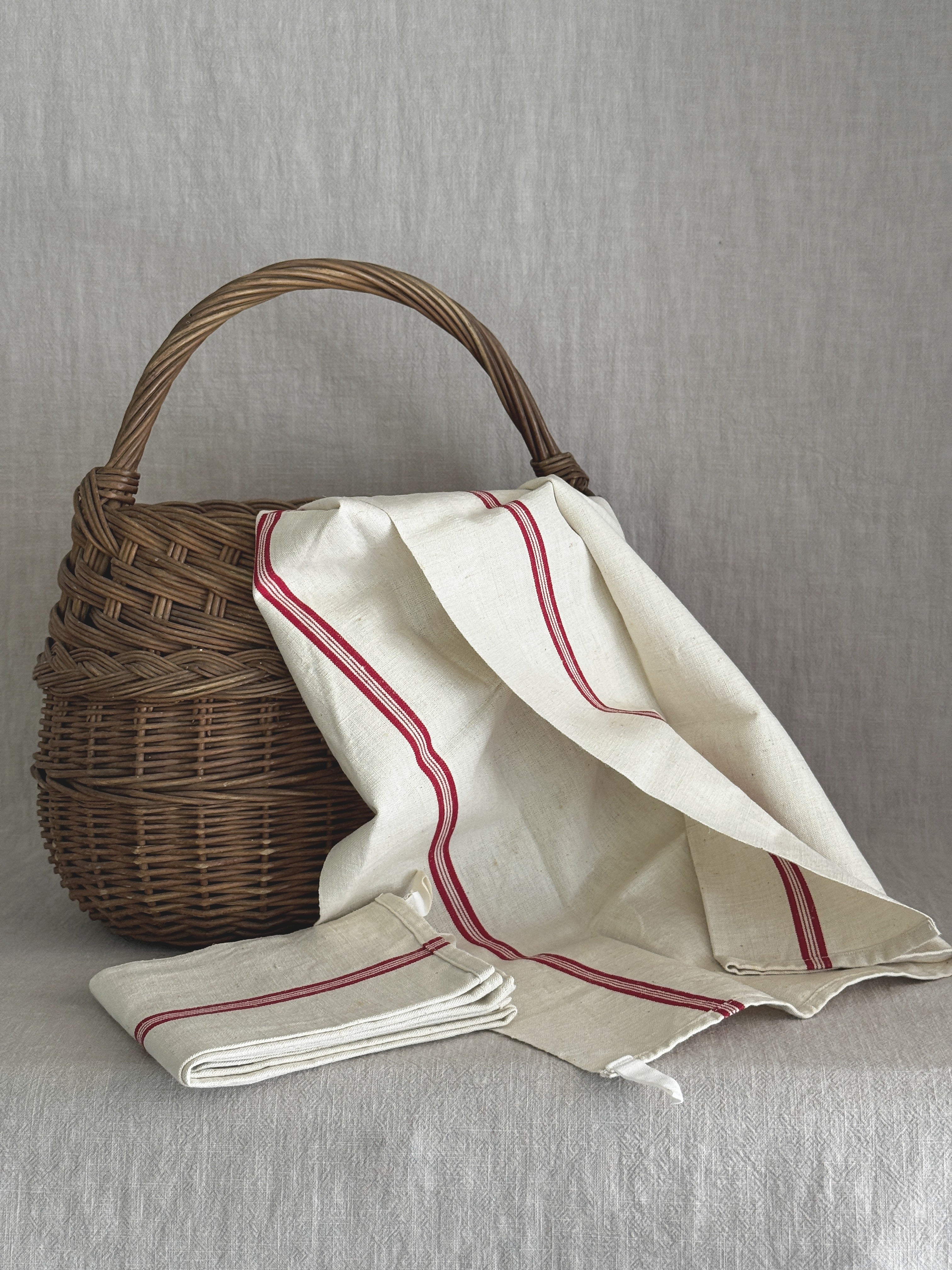 Red-striped French linen torchon draped over a woven basket with a second folded towel beside it