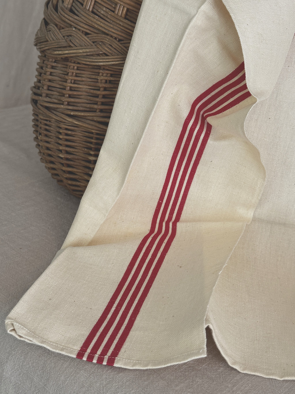 Close view of a crisp French toile metis tea towel showing five fine red woven stripes and the hemmed edge