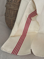 Close view of a crisp French toile metis tea towel showing five fine red woven stripes and the hemmed edge
