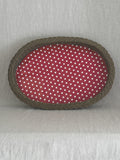 Large oval willow basket tray seen from above, lined with red and white polka dot oilcloth, on a linen cloth