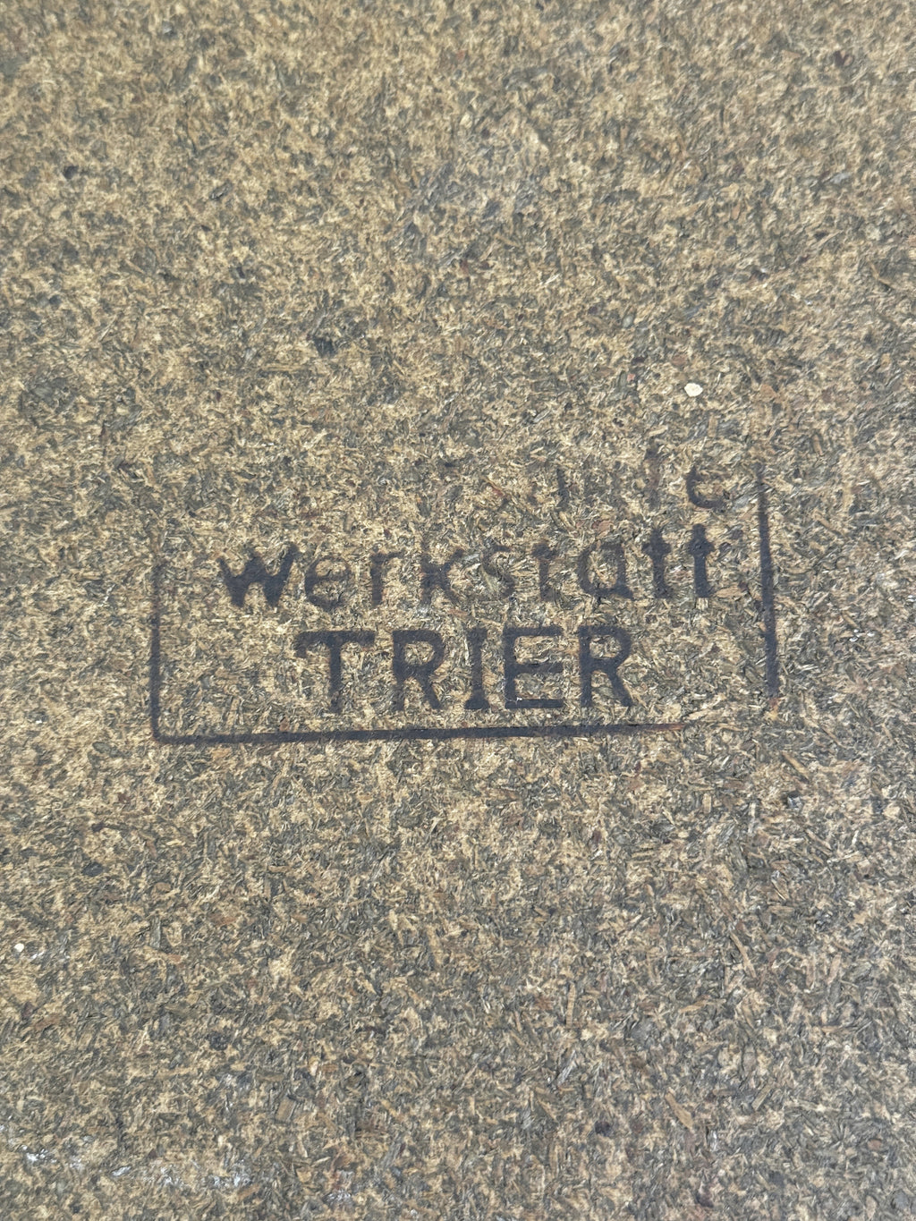 Faded rubber stamp on the fibreboard base reading werkstatt TRIER inside a rectangular frame