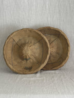 Two vintage French bannetons standing upright, showing the flour-patinated striped linen liners inside