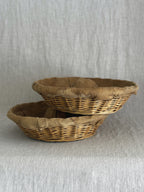 Two round willow bread proofing baskets stacked at an angle, linen liners folded over the woven rims