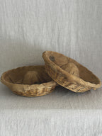 Pair of French banneton baskets side by side on a linen backdrop, one tipped to show the lining