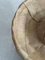 Detail of the linen liner inside a banneton, showing the narrow blue woven stripe and metal staples at the rim