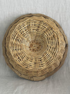 Underside of a round French banneton showing the spiral-woven willow base and the linen edge