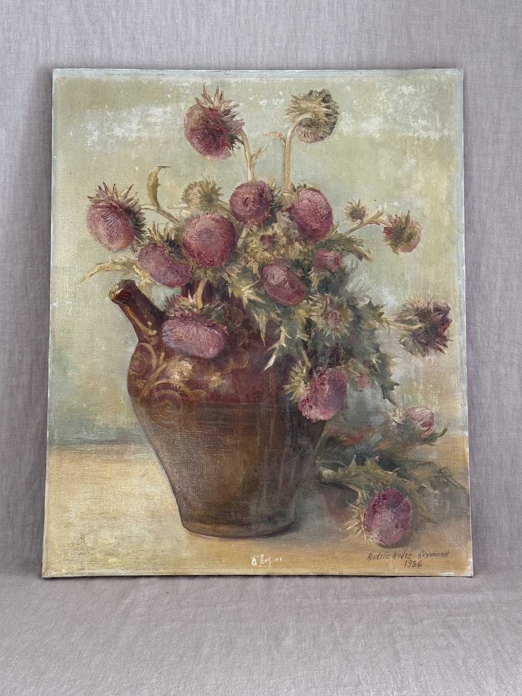 Vintage French still life oil painting from 1956, a bouquet of dusty pink thistles in a brown glazed earthenware jug, unframed canvas against a grey linen backdrop