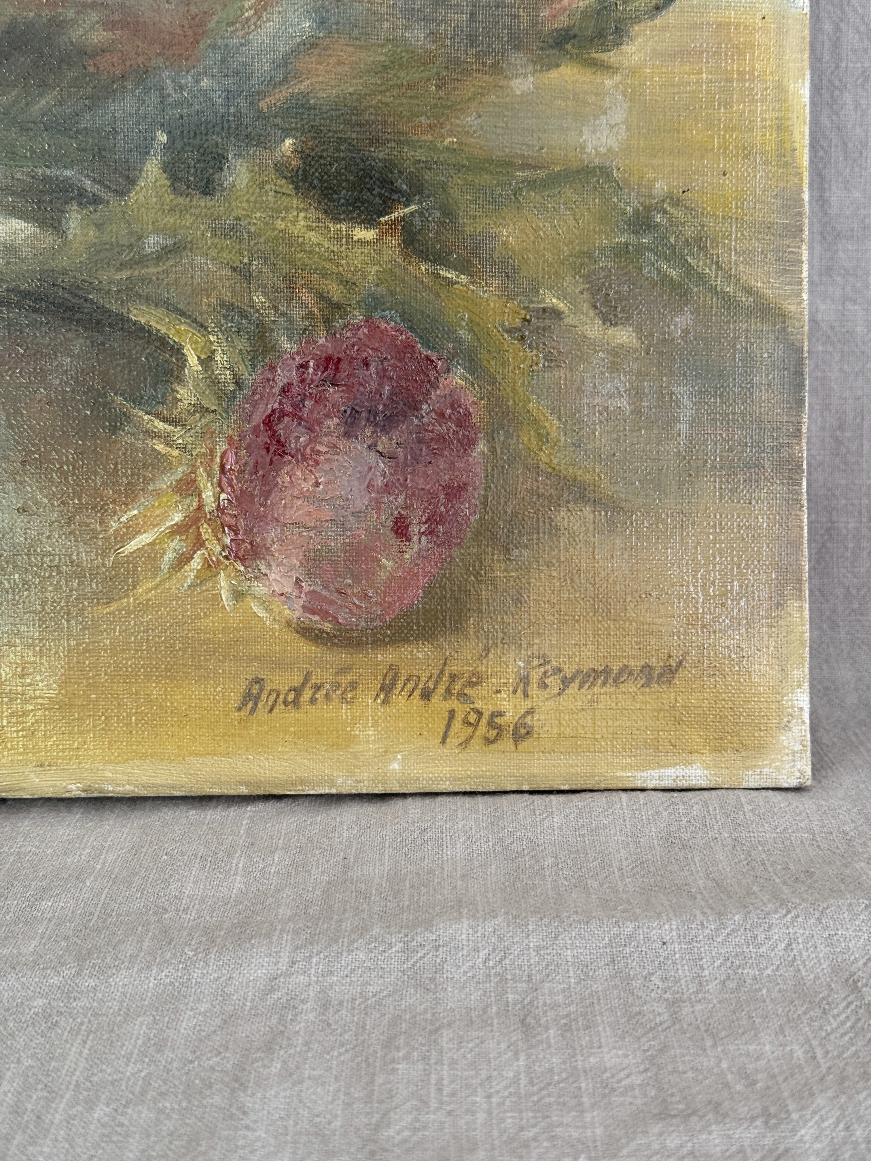 Close view of the lower right of the painting showing the signature Andree Andre-Reymond and the date 1956 written in dark paint on the ochre tabletop