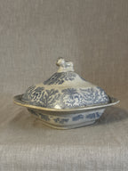 Side view of the blue transferware covered dish showing the lid, lion finial and pastoral pattern