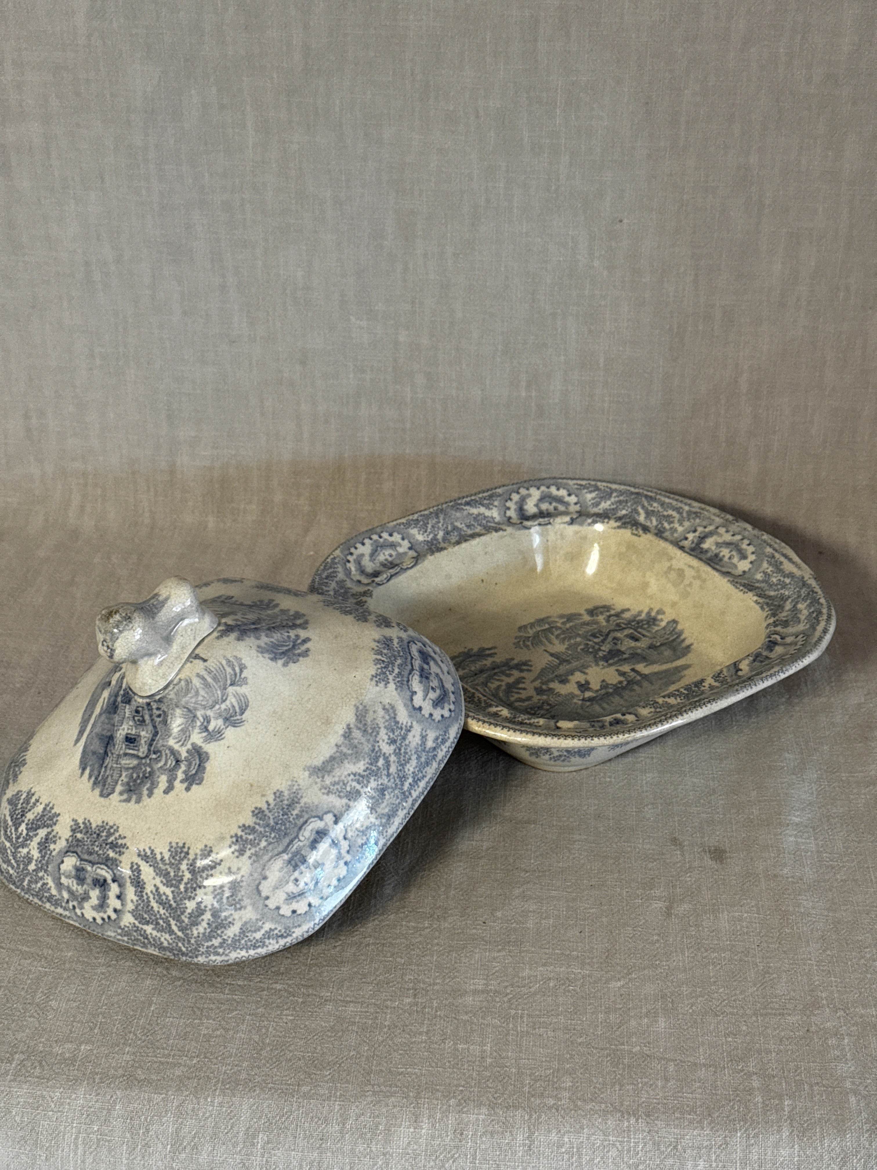 The covered dish with the lid lifted off, showing both halves of the blue transfer pattern
