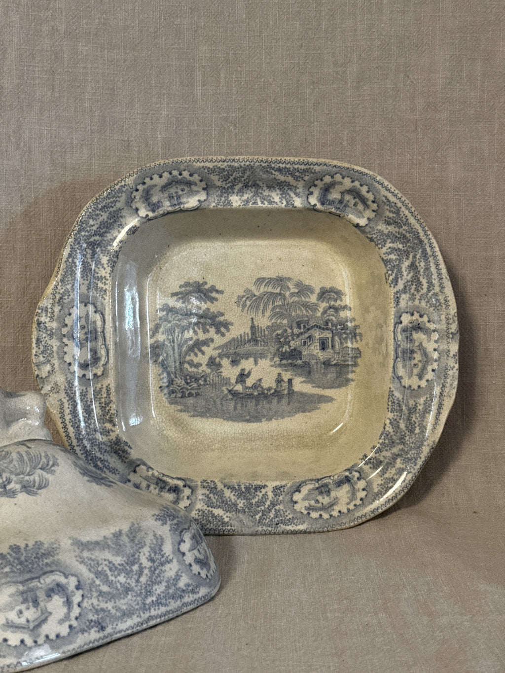 Interior of the transferware dish showing the printed pastoral scene with palms and a boat