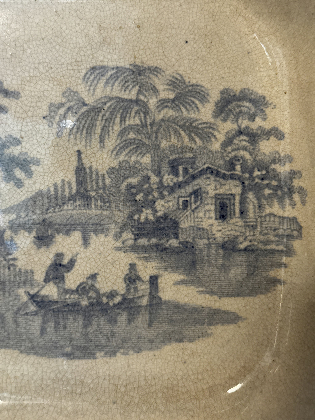 Detail of the blue transfer pattern showing palms, a pagoda and figures in a boat