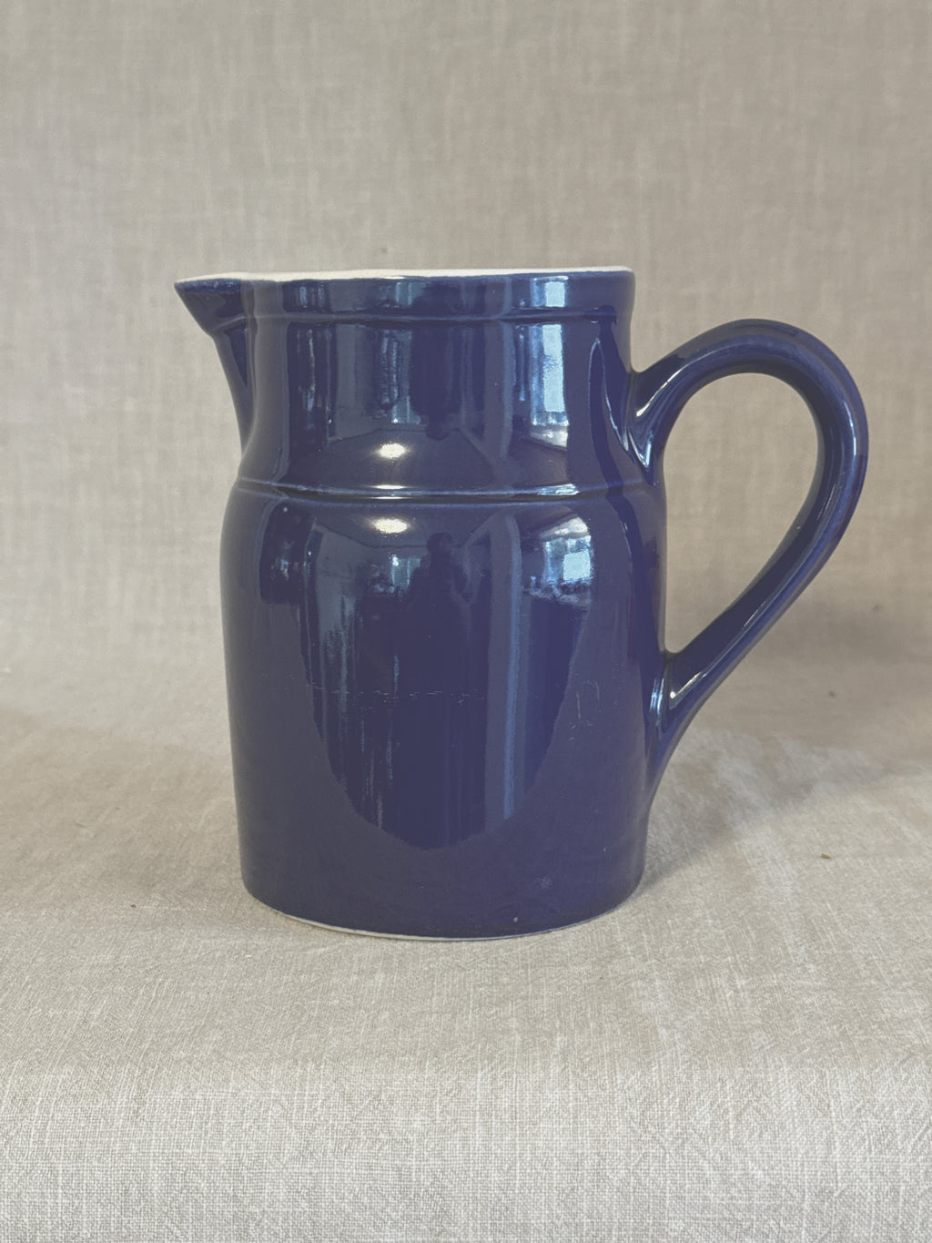 Side view of the blue Digoin stoneware pitcher showing the strap handle