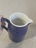 The Digoin pitcher held in the hand, showing the white glazed interior