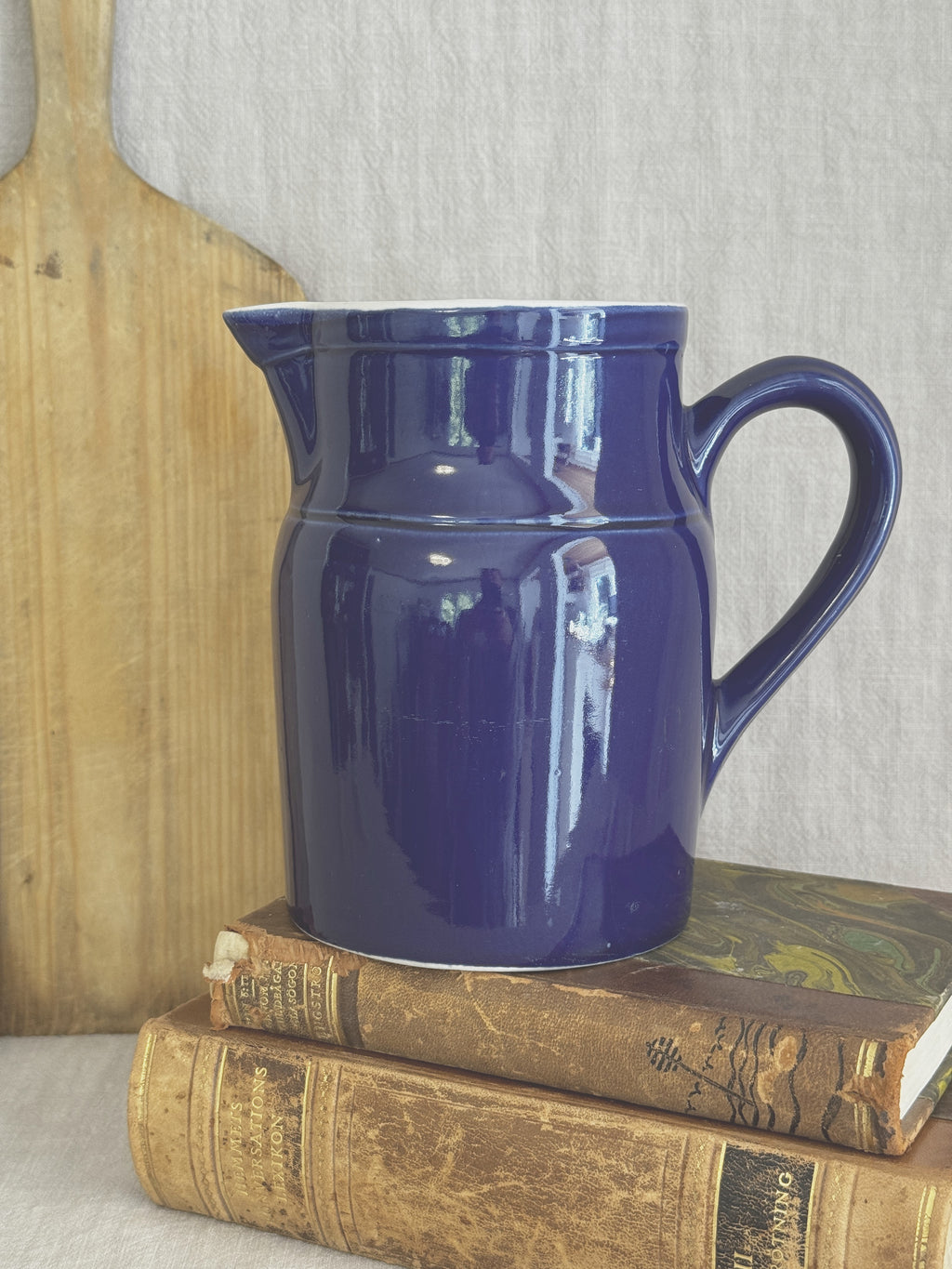 Vintage Digoin Grespots French stoneware pitcher in cobalt blue, shown on a bread board and old books for scale
