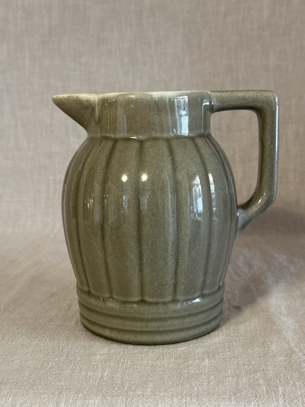 Ribbed jug in soft olive green glaze with a broad strap handle