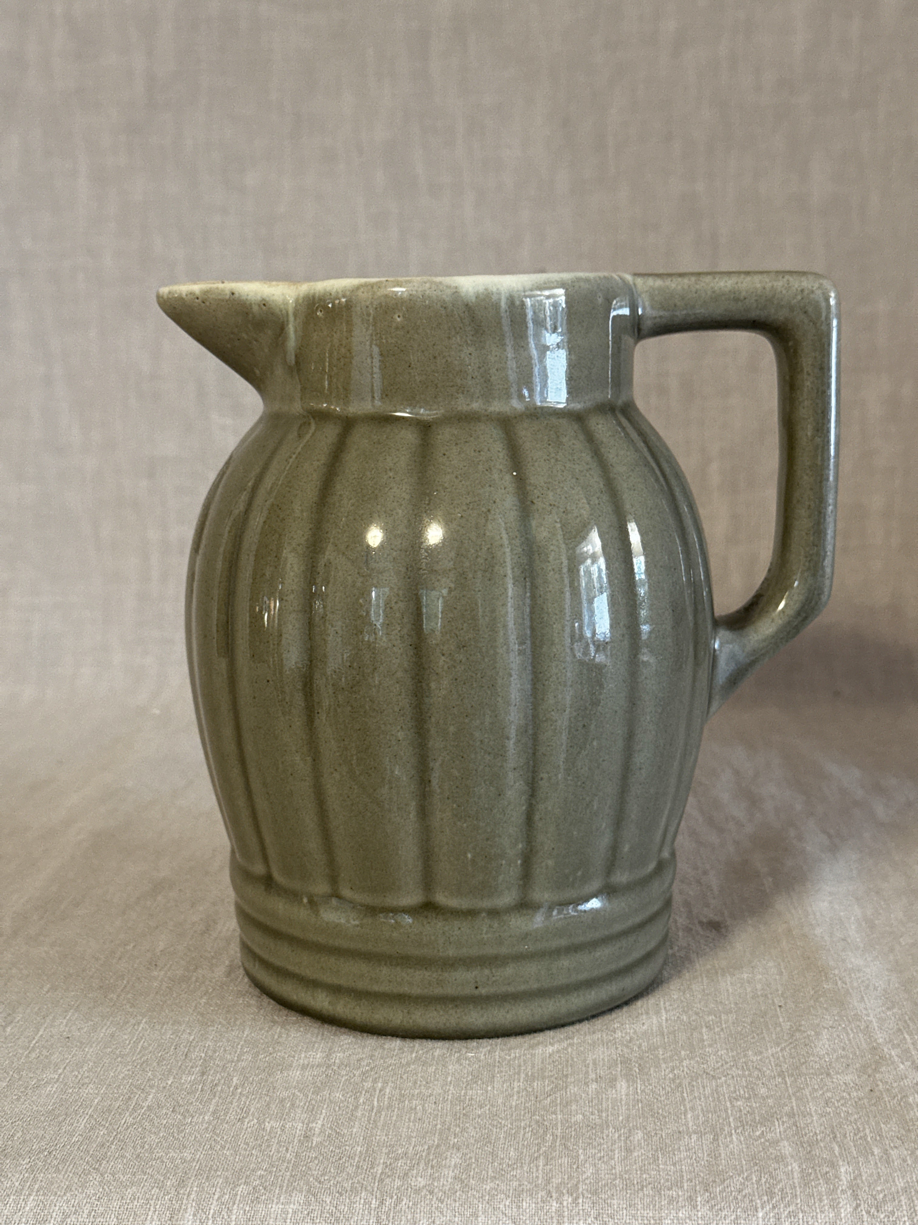 Ribbed jug in soft olive green glaze with a broad strap handle