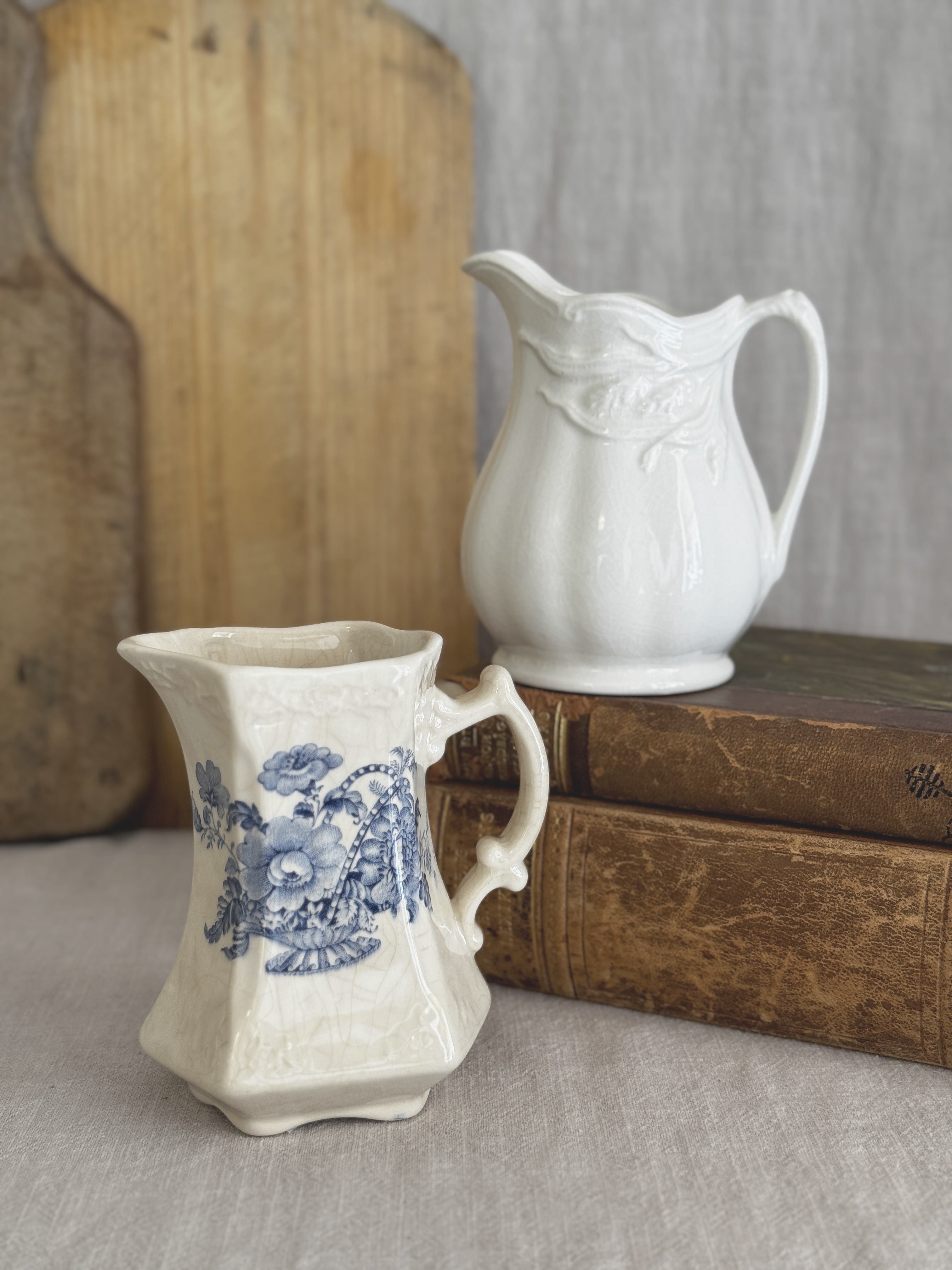 Pair of vintage English cream jugs, Crown Devon and Royal Crownford, shown together on antique books and a bread board for size reference