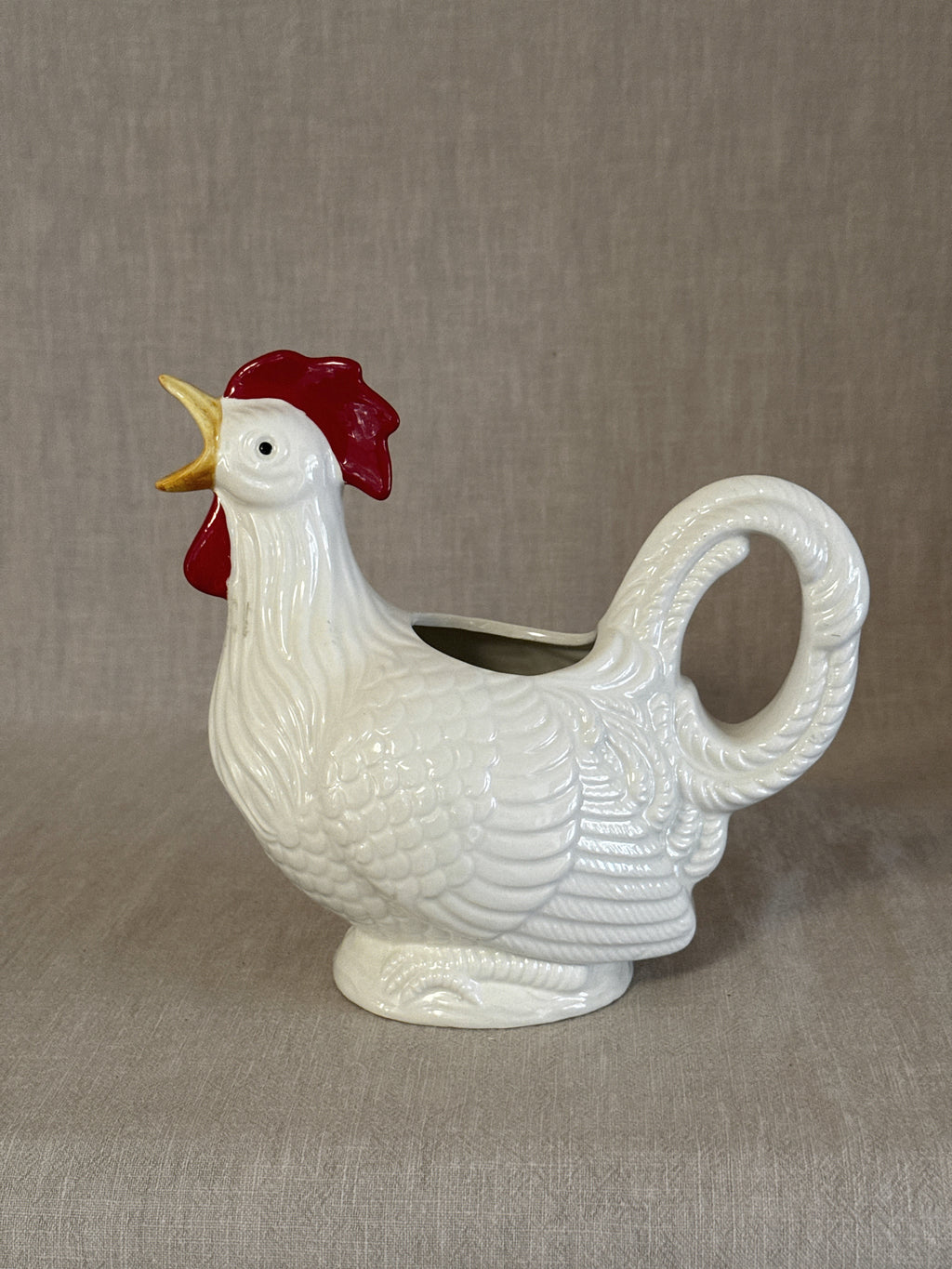 Side view of the rooster jug showing the sweeping tail that forms the handle
