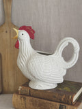 White rooster-form jug, styled with an antique bread board and books