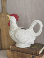 White rooster-form jug, styled with an antique bread board and books