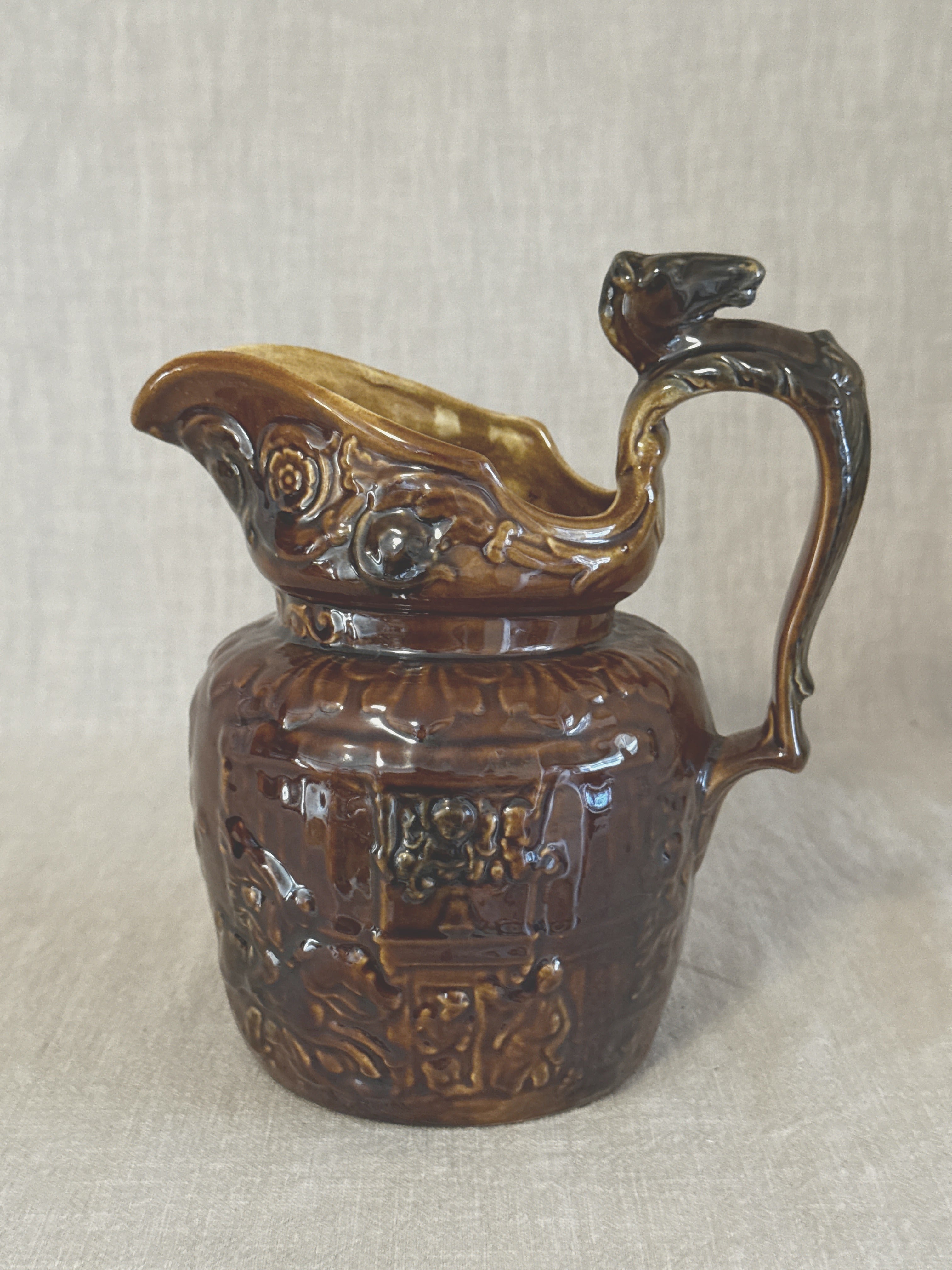 Side view of the treacle glazed relief jug showing the hunting scene and the arched horse handle