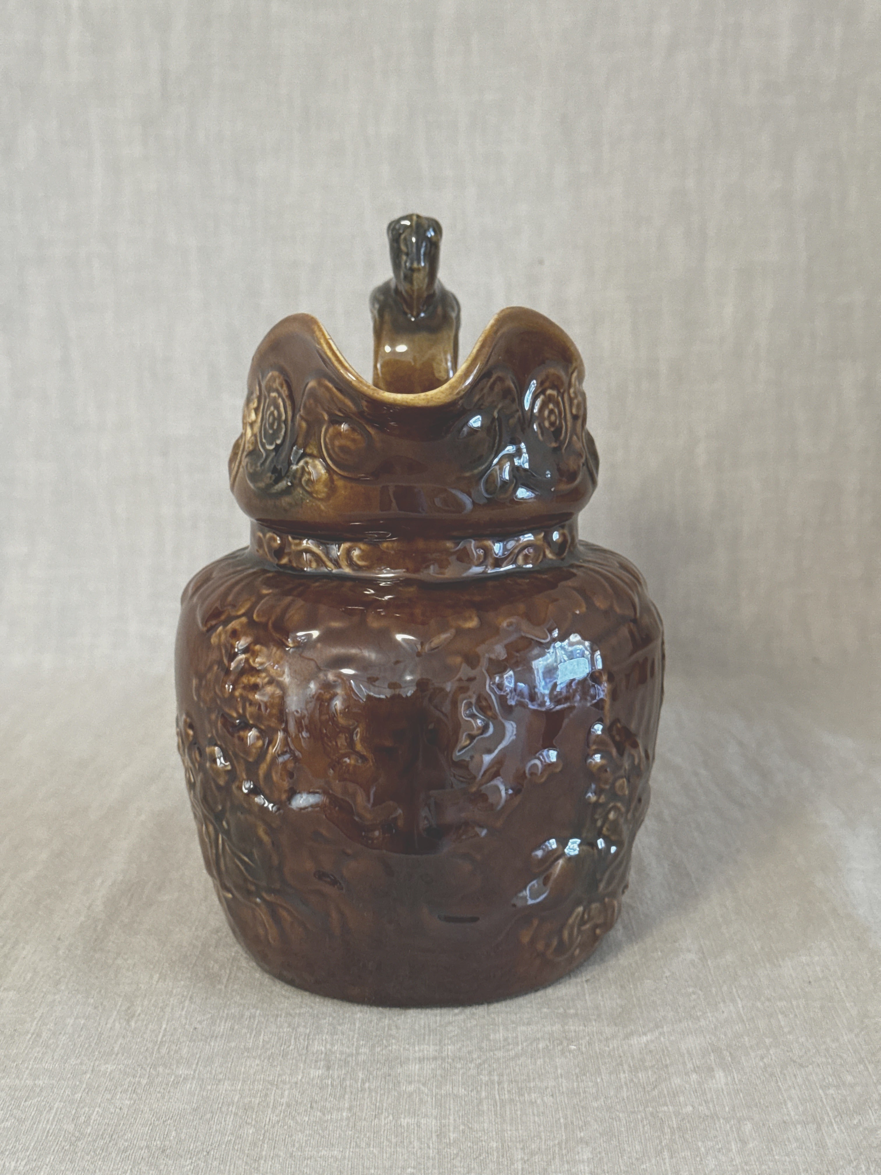 Front view of the treacle glazed relief jug showing the shaped spout and moulded neck