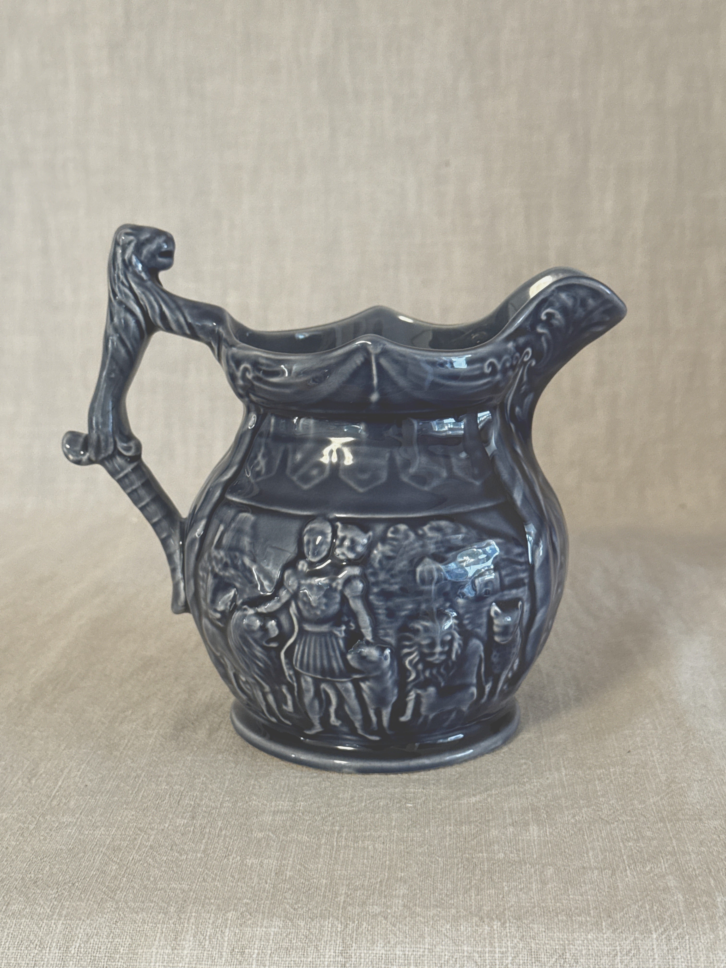 Vintage English blue relief jug with a mask handle and a frieze of figures, Staffordshire earthenware