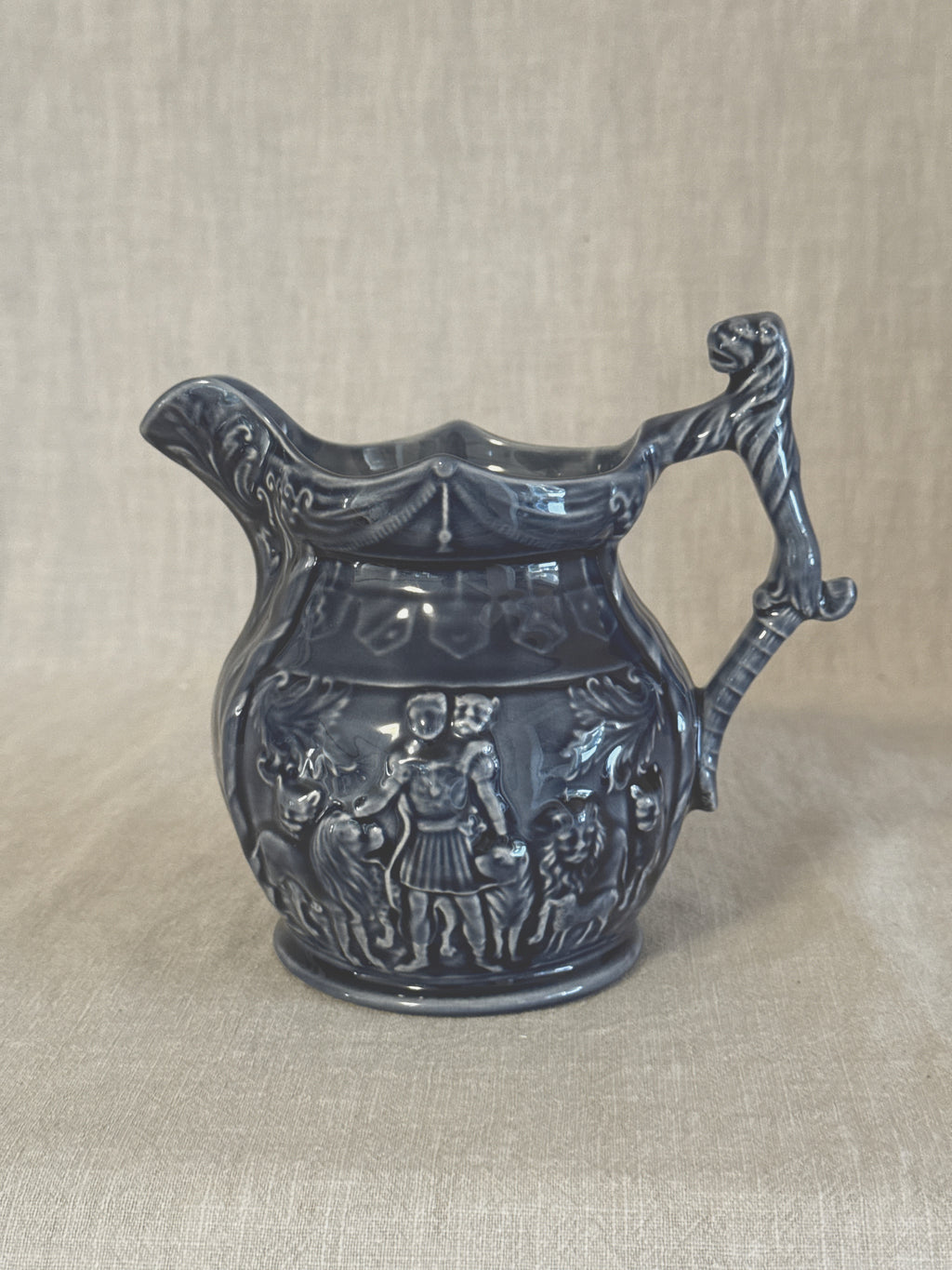 Side view of the blue relief jug showing the figure frieze and the mask at the top of the handle