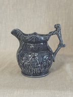 Side view of the blue relief jug showing the figure frieze and the mask at the top of the handle