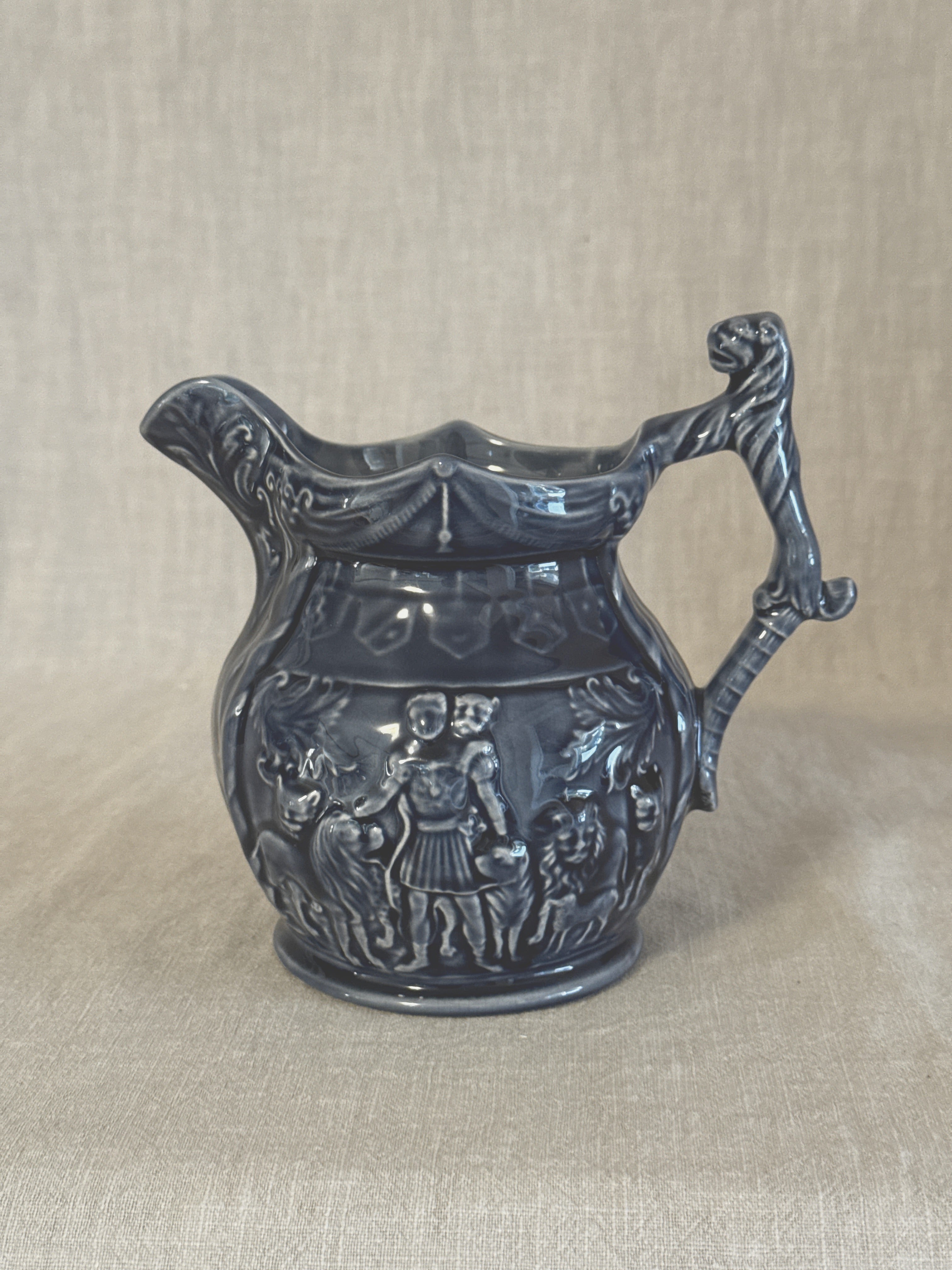 Side view of the blue relief jug showing the figure frieze and the mask at the top of the handle